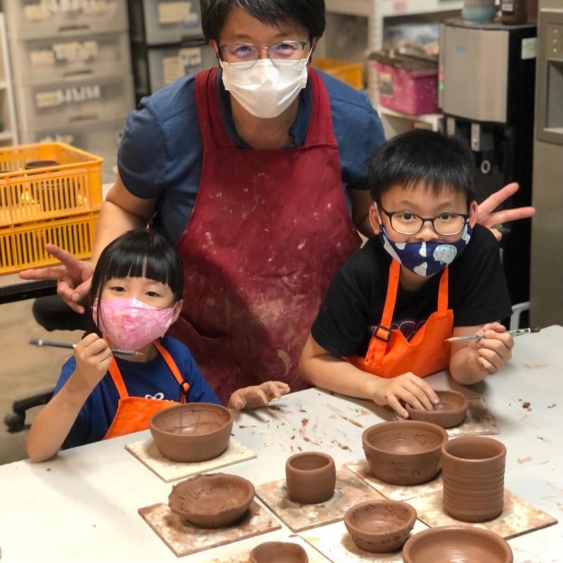 children and adult at pottery class