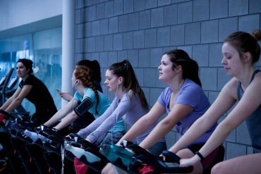 women on stationary bikes in gym