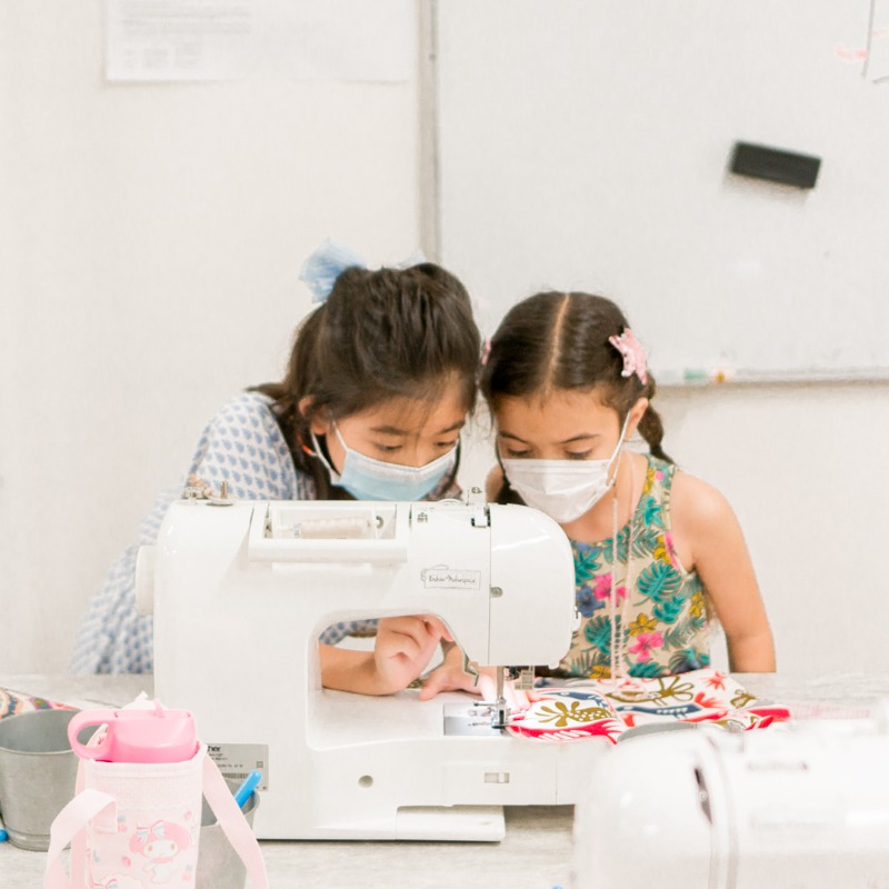 two girls at a sewing class machine