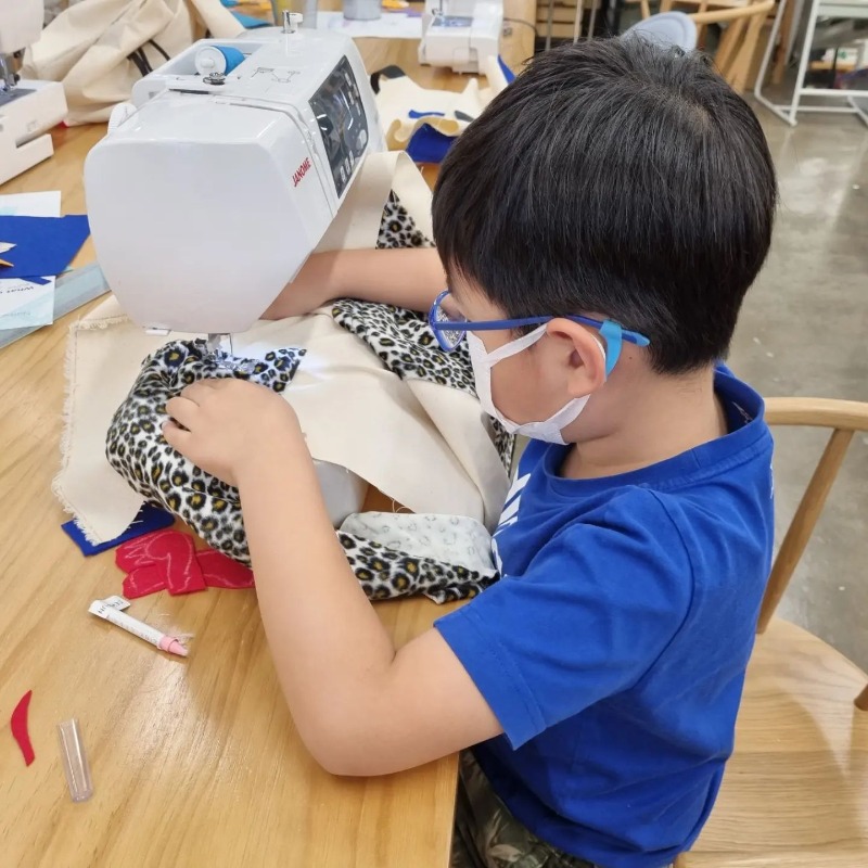 little boy using sewing machine