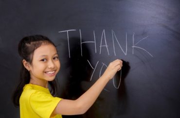 girl writing thank you on chalkboard