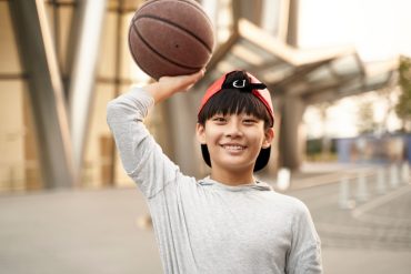 portrait of a happy fifteen-year-old asian teenage basketball player