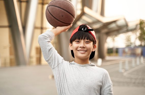 portrait of a happy fifteen-year-old asian teenage basketball player