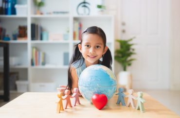 Asian little girl smiling behind the people, heart, globe model play toys