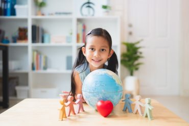 Asian little girl smiling behind the people, heart, globe model play toys