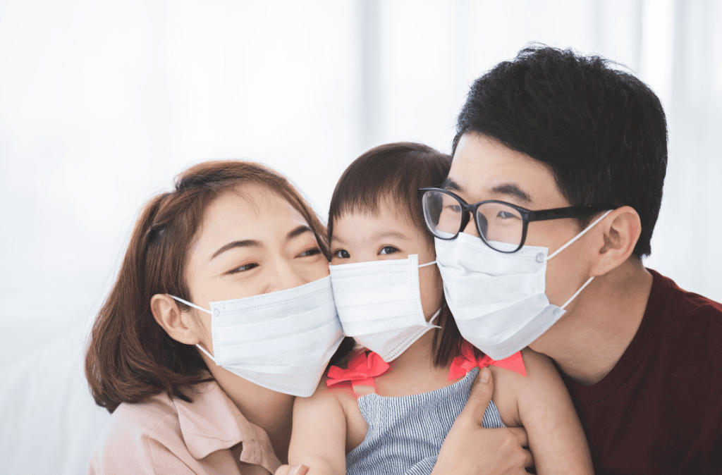 Asia Family in medical masks on the face looks at the camera while standing in the living room at home